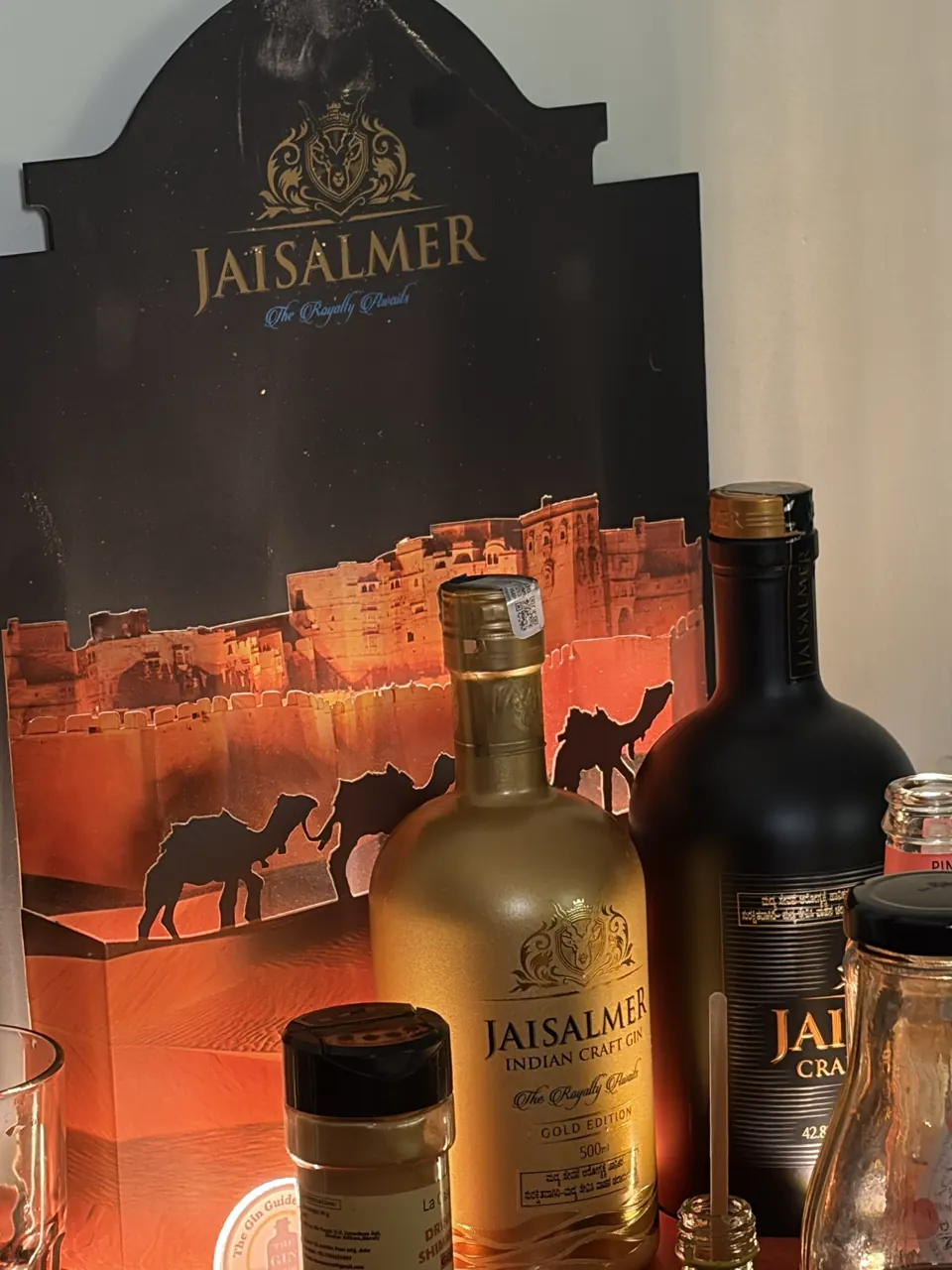 Bottles of Jaisalmer Indian Craft Gin in front of an illustrated desert-and-camels display