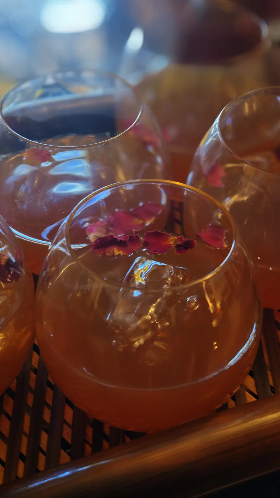Close-up of whisky cocktails over ice in stemless glasses, scattered with dried rose petals