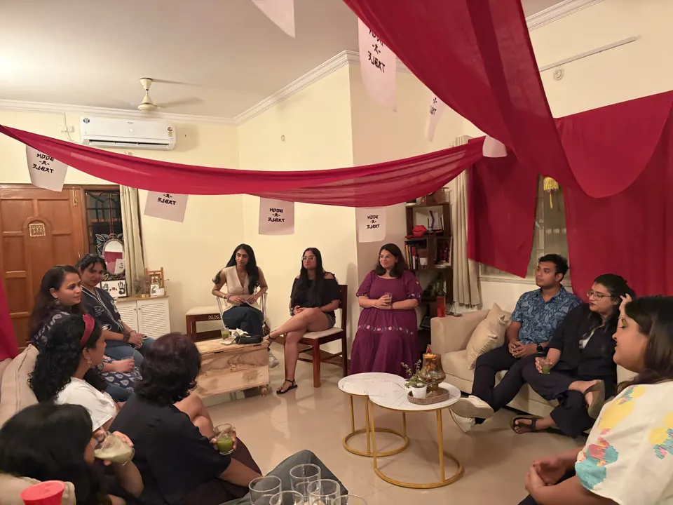 Guests sit in a circle of sofas and chairs beneath crimson drapes and hand-lettered Book-A-Table bunting